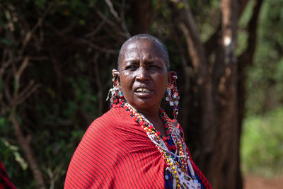 Portrait of smiling woman standing against trees