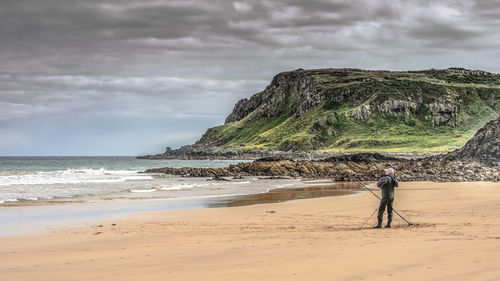 Man standing at beach against sky