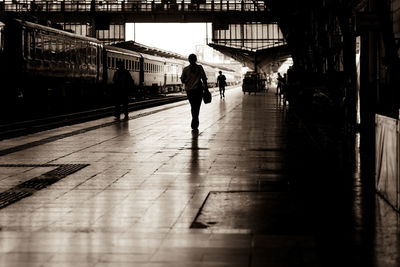 Rear view of man walking at railroad station