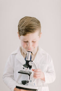 Young child in labcoat looking into a microscope