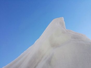 Low angle view of snow against clear blue sky