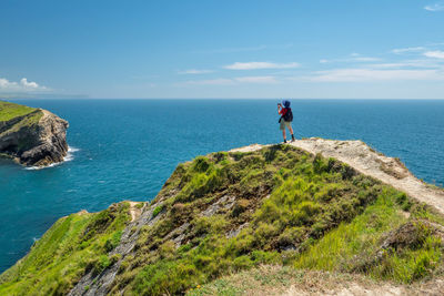 Rear view of man walking on mountain against sky