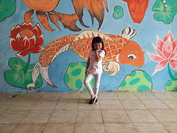 Full length of girl standing against graffiti wall