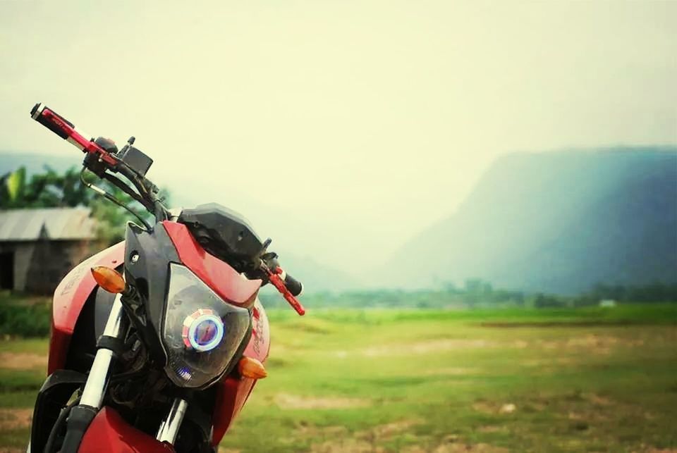 transportation, mode of transport, focus on foreground, land vehicle, clear sky, landscape, field, mountain, close-up, day, nature, outdoors, travel, sky, bicycle, grass, one person, copy space, selective focus, part of