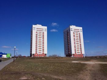 Field by building in city against sky