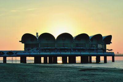 Silhouette pier over sea against sky during sunset