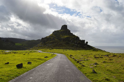 Road amidst green landscape against sky