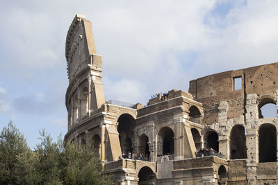 Low angle view of coliseum against cloudy sky