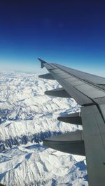 Airplane wing against clear sky during winter