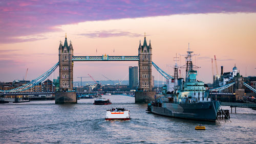 Boats on thames river against tower bridge during sunset in city