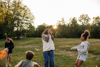 Kids having fun while playing with female counselor in playground at summer camp