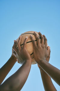 Cropped image of hand against clear blue sky