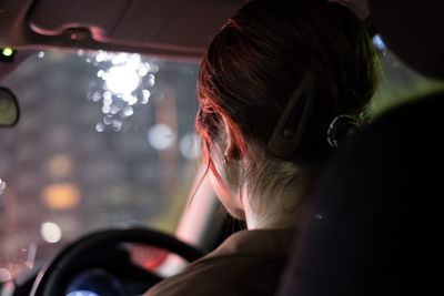 Rear view of woman driving car at night