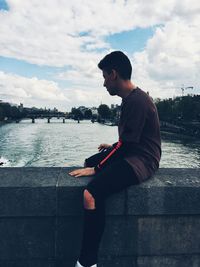 Man sitting on shore against sky