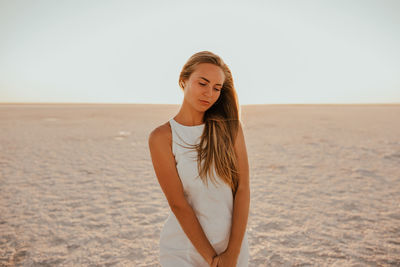 Portrait of young woman standing at beach