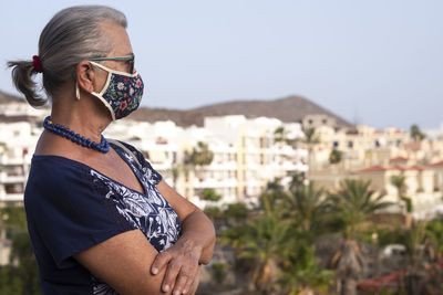 Midsection of woman with sunglasses standing against sky