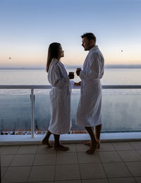 Rear view of couple standing at beach against clear sky
