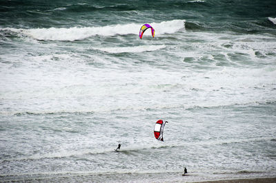 Person paragliding over sea against sky