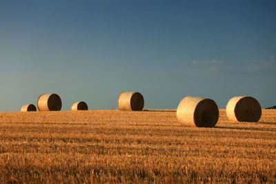 Hay bales on field against sky