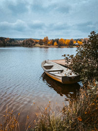 Boat moored in lake against sky