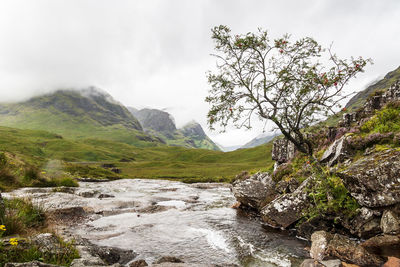 Scenic view of river amidst mountains against sky