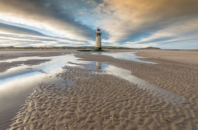 Lighthouse on beach against sky