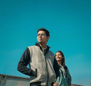 Young man standing against clear blue sky