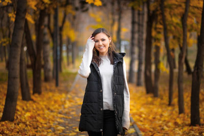 Portrait of woman standing in forest during autumn