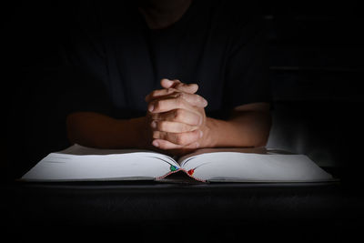 Midsection of man reading book in darkroom