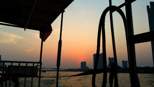 Silhouette built structure by sea against sky during sunset