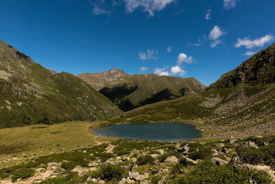 Scenic view of mountains by pond against sky