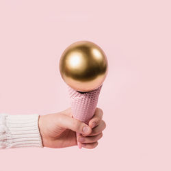 Close-up of hand holding ice cream against gray background