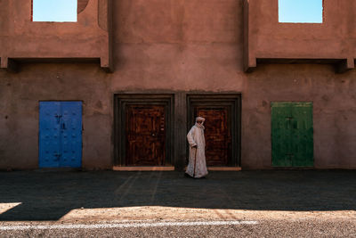 Rear view of woman standing by building