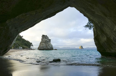 Te hoho rock seen through a rock arch at a coastal area named cathedral cove