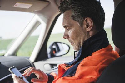 Engineer using smart phone sitting in car