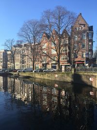 Canal by buildings against sky in city