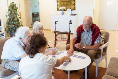 Senior friends playing cards at table in nursing home