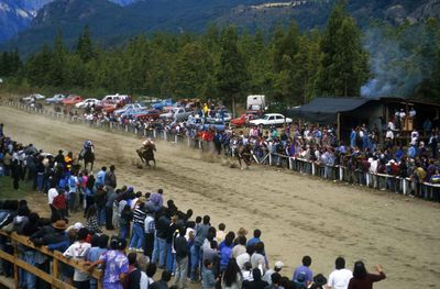 Crowd watching horse racing against trees