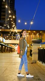 Portrait of young woman standing in city at night