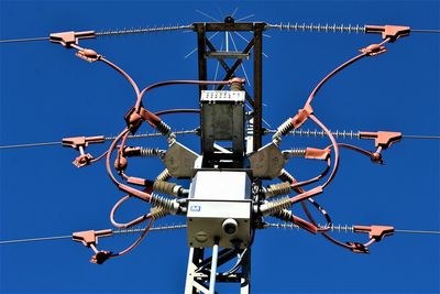 Low angle view of telephone pole against clear blue sky