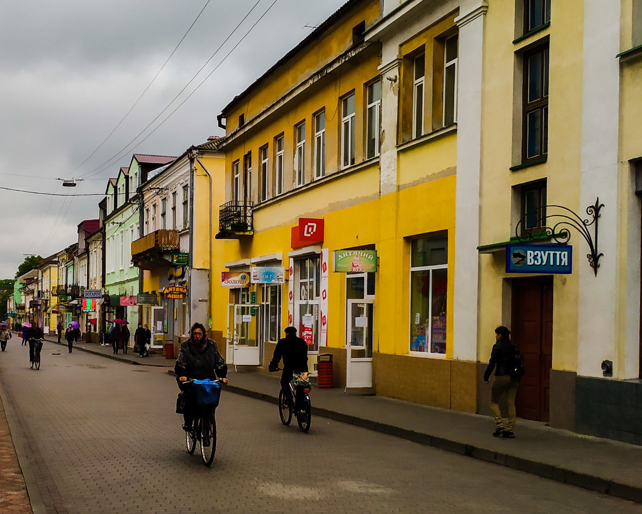 PEOPLE RIDING BICYCLES ON ROAD BY BUILDINGS IN CITY