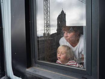 Side view of woman looking through window