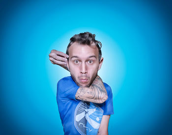 Digitally generated image of man holding ear against blue background