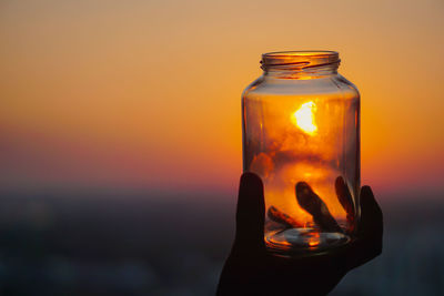 Close-up of glass bottle against orange sky