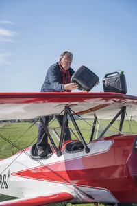 Germany, dierdorf, senior man standing on biplane with petrol canisters