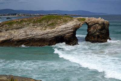 Rock formation in sea against sky