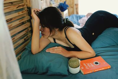 Thoughtful young woman lying on bed at home