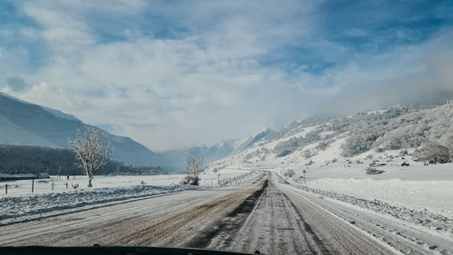 Road leading towards snowcapped mountains against sky