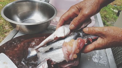 Cropped image of person preparing fish on barbecue grill