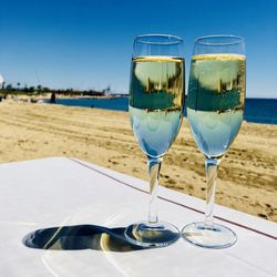 Wine glasses on table at beach against sky